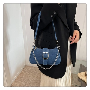 Dettaglio della borsa baguette in denim blu con catena d'argento e cuciture bianche