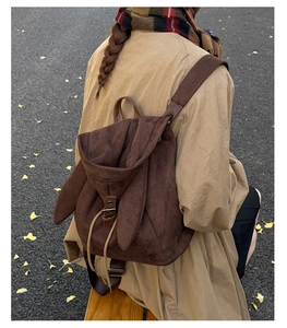 Detail of dark brown faux suede backpack featuring cute rabbit ears and drawstring closure