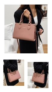 Detail view of pink lychee grain leather handbag with gold hardware and logo branding