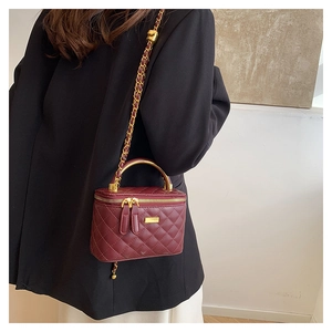 Macro detail of wine red quilted faux leather mini bag with gold chain and metal handle