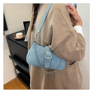 Dettaglio borsa a spalla in denim azzurro con fibbia argento e catena in metallo