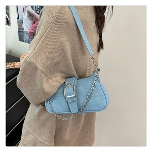 Dettaglio della borsa a spalla in denim azzurro con fibbia argento e catena metallica
