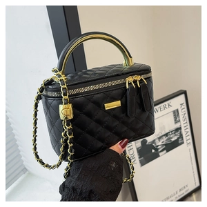 Detailed macro of black quilted crossbody bag with gold metal handle and chain strap