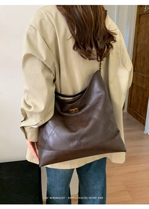 Makroaufnahme der dunkelbraunen Stepptasche mit goldenem Drehverschluss und Kettenriemen