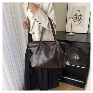 Detail of soft brown leather tote bag featuring star studs and vertical shoulder straps