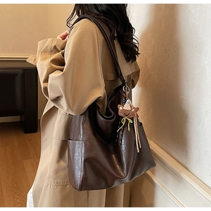 Détail du grand sac cabas vintage marron avec breloque ours et poche latérale