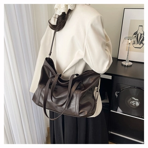 Detail of soft brown leather tote bag with long shoulder strap in minimalist home setting