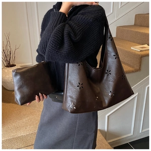 Detail of dark brown tote bag set with laser-cut flower patterns and small clutch