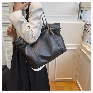 Detail shot of black tote bag with premium leather texture and elegant metal buckle accent