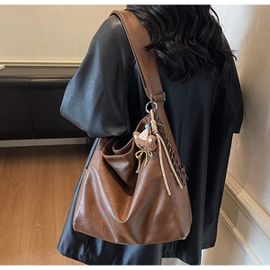 Détail du sac à main marron avec charm ours en peluche et pompon tissé élégant