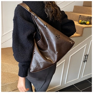 Detail of laser-cut flower patterns on dark brown leather hobo bag for women