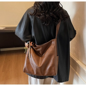 Vue arrière d'un mannequin portant un grand sac cabas vintage marron avec bijou d'ours