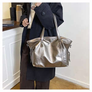 Detail of metallic bronze leather tote bag with stylish side tassels and side ring buckles