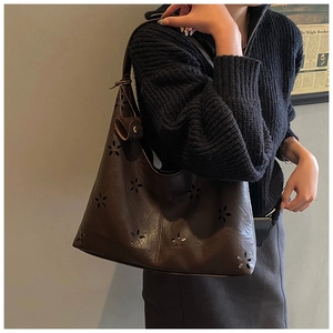 Detailed close-up of dark brown hollowed-out faux leather shoulder bag with floral patterns