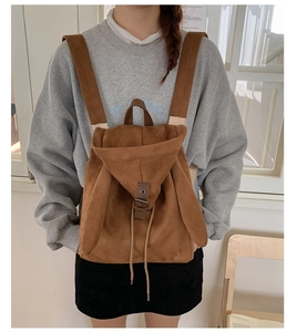 Detalle de una mochila de ante marrón con orejas de conejo y cordón llevada por una modelo