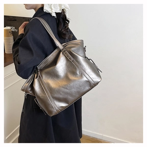 Detailed side view of a large silver metallic tote bag worn by a model in a casual setting