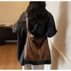 Détail d'un sac cabas marron en cuir vintage avec bandoulière large et pendentif ours