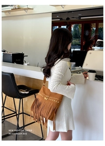 Gros plan d'un sac bandoulière en daim marron avec franges rétro et rivets dorés