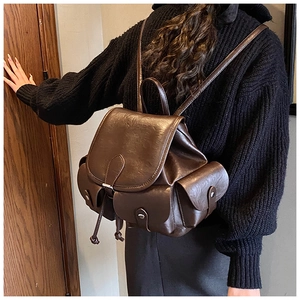 Detail of vintage brown PU leather backpack with magnetic buckle and drawstring closure