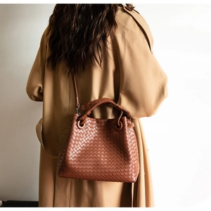 Close-up of brown woven leather handbag detail with metallic eyelets and shoulder strap