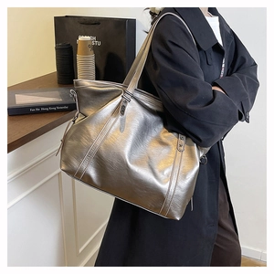 Detail of silver metallic tote bag with star studs and wide strap on model