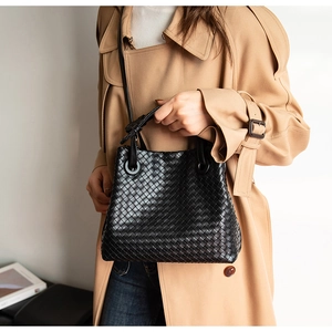 Detail of black woven leather handbag with classic Intrecciato pattern and metal rings