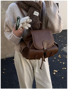 Detail of a brown vintage-style PU leather backpack with drawstring and flap closure