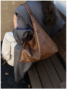 Detail of laser-cut hollow floral pattern on caramel brown leather tote bag