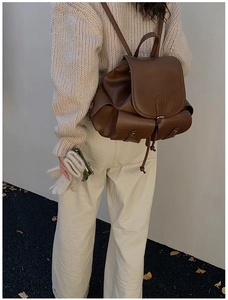 Outdoor shot of dark brown pleated leather backpack with utility pockets on a model