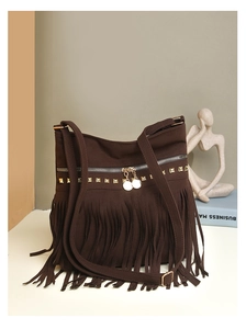 Détail d'un cabas en daim marron foncé avec rivets dorés et longues franges bohèmes