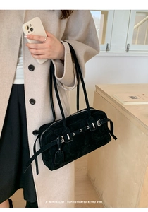 Minimalist black suede shoulder bag featuring silver metal eyelets and retro buckle detail