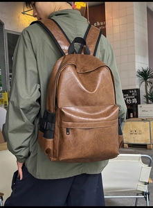 Brown PU leather backpack detail showing textured surface and side mesh pocket in use