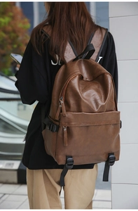 Detail view of a vintage brown leather backpack featuring large capacity and smooth texture
