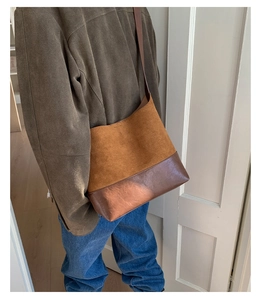 Detail view of retro bucket bag showing dual-texture brown leather and smooth stitching