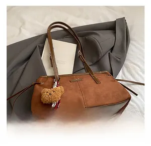 Detailed view of brown faux suede tote bag with stitch lines and cute bear charm decoration