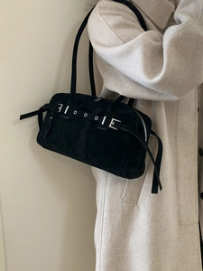 Chic black suede shoulder bag with eyelet belt details and silver hardware on a model