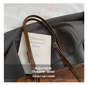 Detail of adjustable shoulder strap on brown suede tote bag with white stitching
