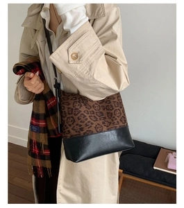 Detail of leopard print bucket bag with black bottom stitching and slim shoulder strap