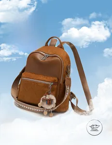 Detail of brown faux leather backpack with quilted pocket and fluffy charm in the sky