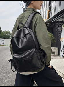 Detail shot of black PU leather backpack showing texture and front zipper pocket