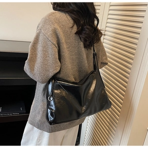 Macro view of glossy black faux leather tote with silver metal ring and strap detail