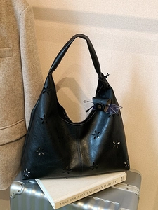 Hollow out black leather shoulder tote bag with laser-cut floral patterns on a silver case