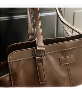 Detailed close-up of dark brown tote bag with premium stitching and gold-tone metal hardware