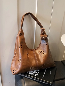 Brown retro hobo bag with laser-cut star patterns and large capacity on book