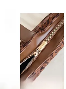 Gros plan du sac cabas léopard avec fermeture éclair dorée lisse et bordure en cuir marron