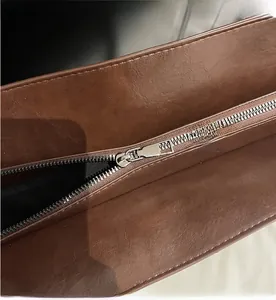 Close-up of smooth silver metal zipper and lychee textured leather on dark brown tote bag