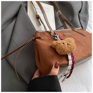 Detail of vintage brown faux suede tote bag with plush bear charm and leather strap