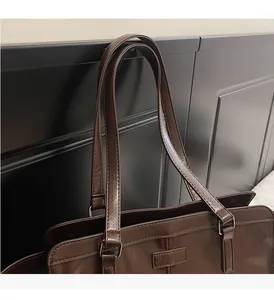 Detail of dark brown tote bag showing smooth PU leather texture and silver buckle