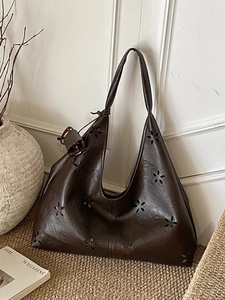 Dark brown oversized hollow-out leather tote bag with floral patterns in a retro style