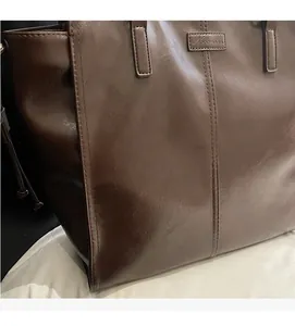 Detail of soft dark brown leather tote bag with vertical stitching and Nevermore logo